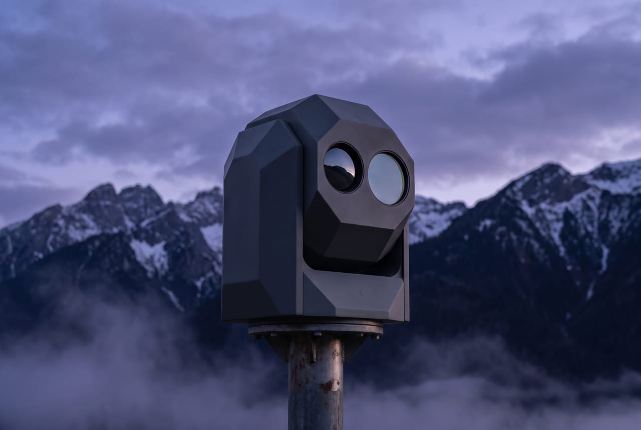 Electro-optical sensor gimbal on a telescopic mast in front of mountains